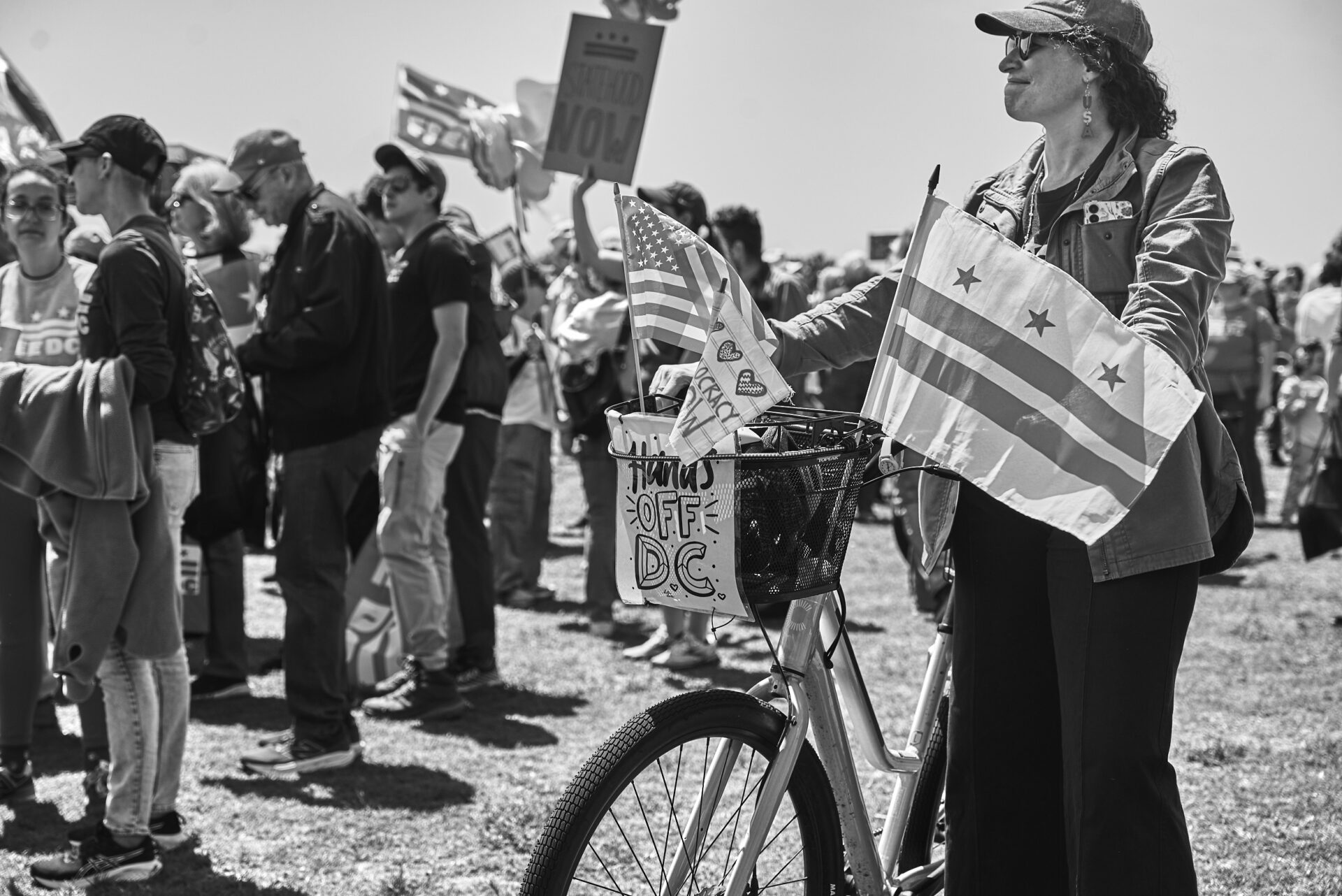 A woman wheeling a bike that has the DC flag on it, and a sign that reads "Hands Off"