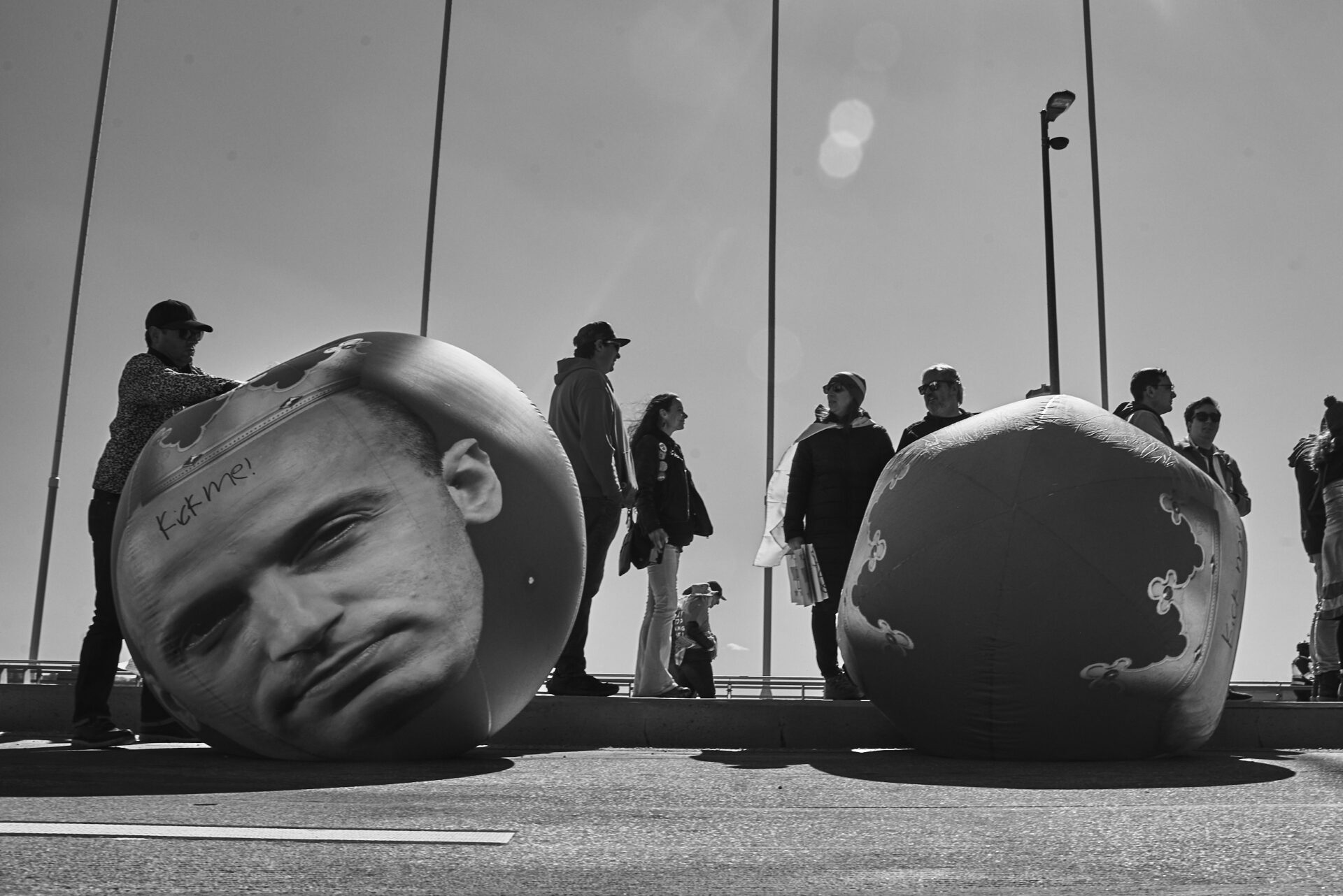 People standing around by big balls of Trump and Stephen Miller's heads that say "kick me"