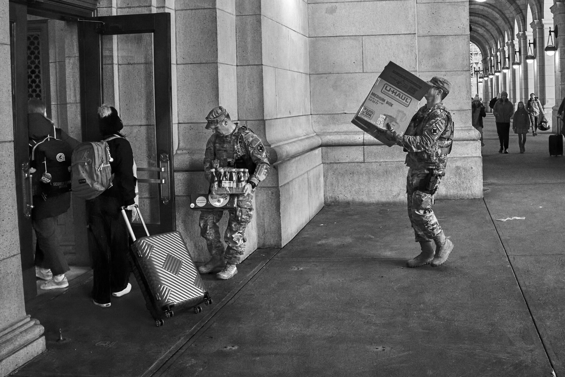 One National Guard member holds open a door for another hauling a box into Union Station