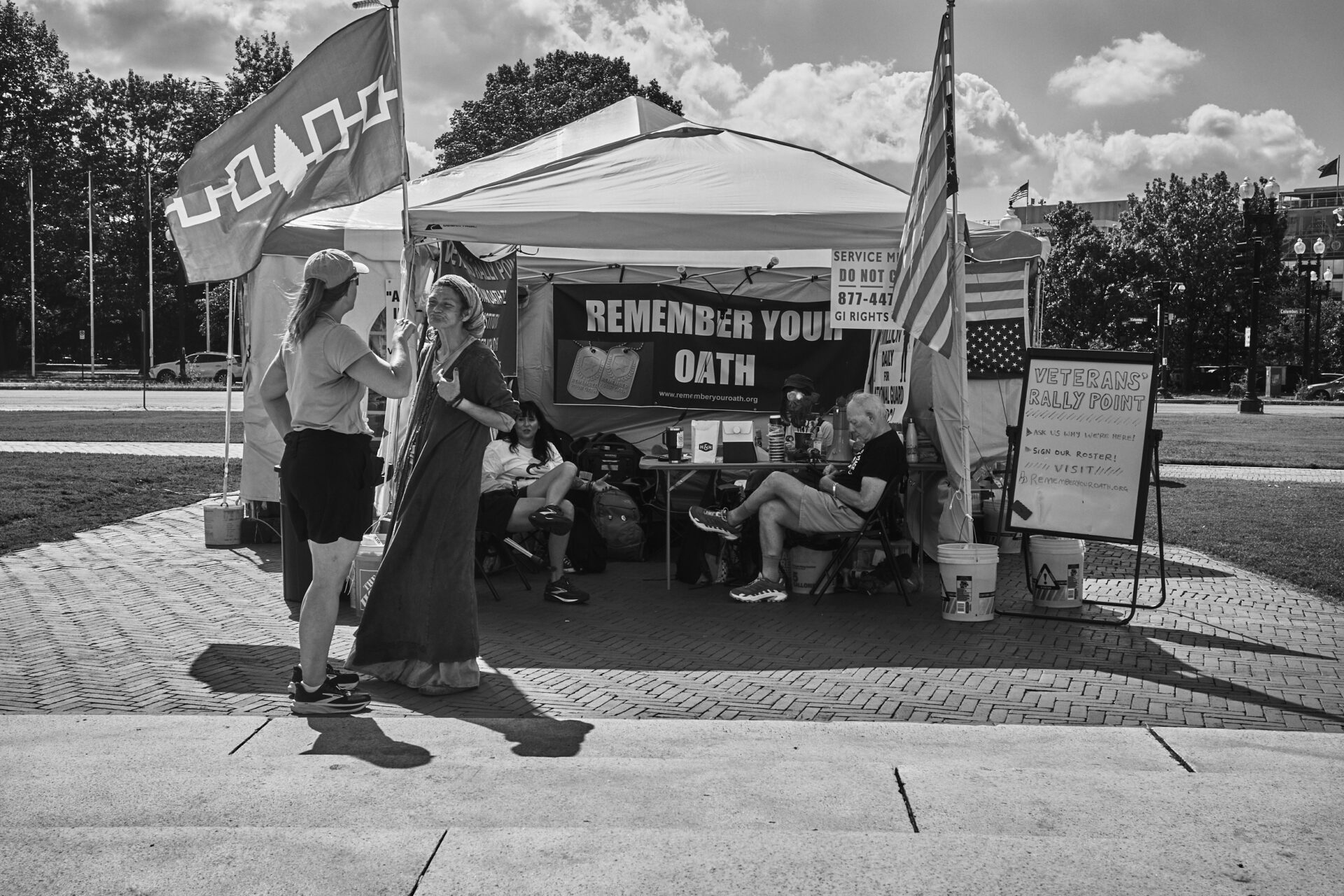 A woman emotes in front of the Remember Your Oath tent, as another woman talks