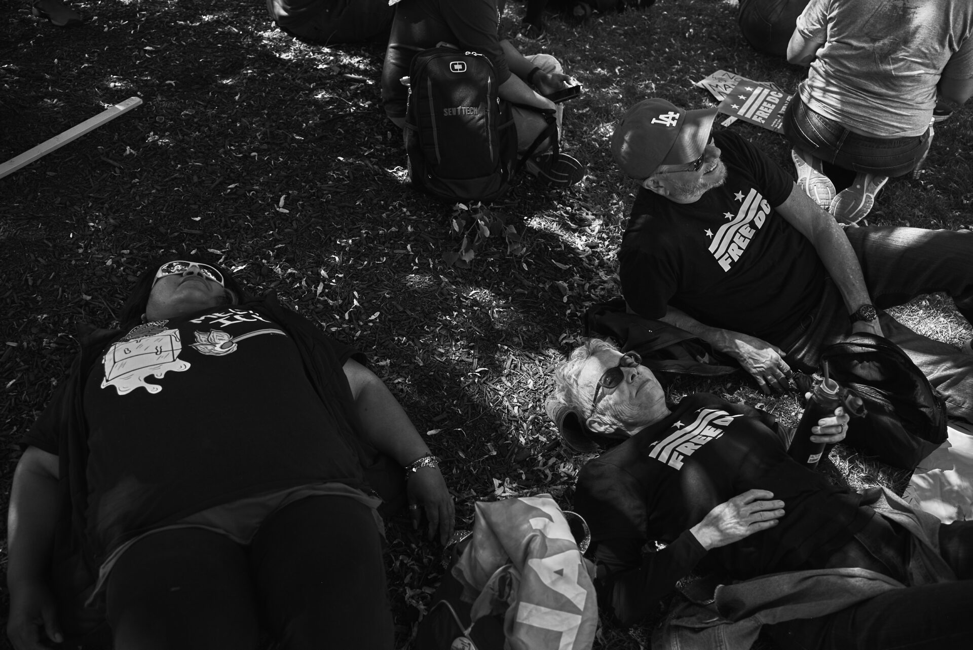 Four protestors laying on the ground in the shade of a tree