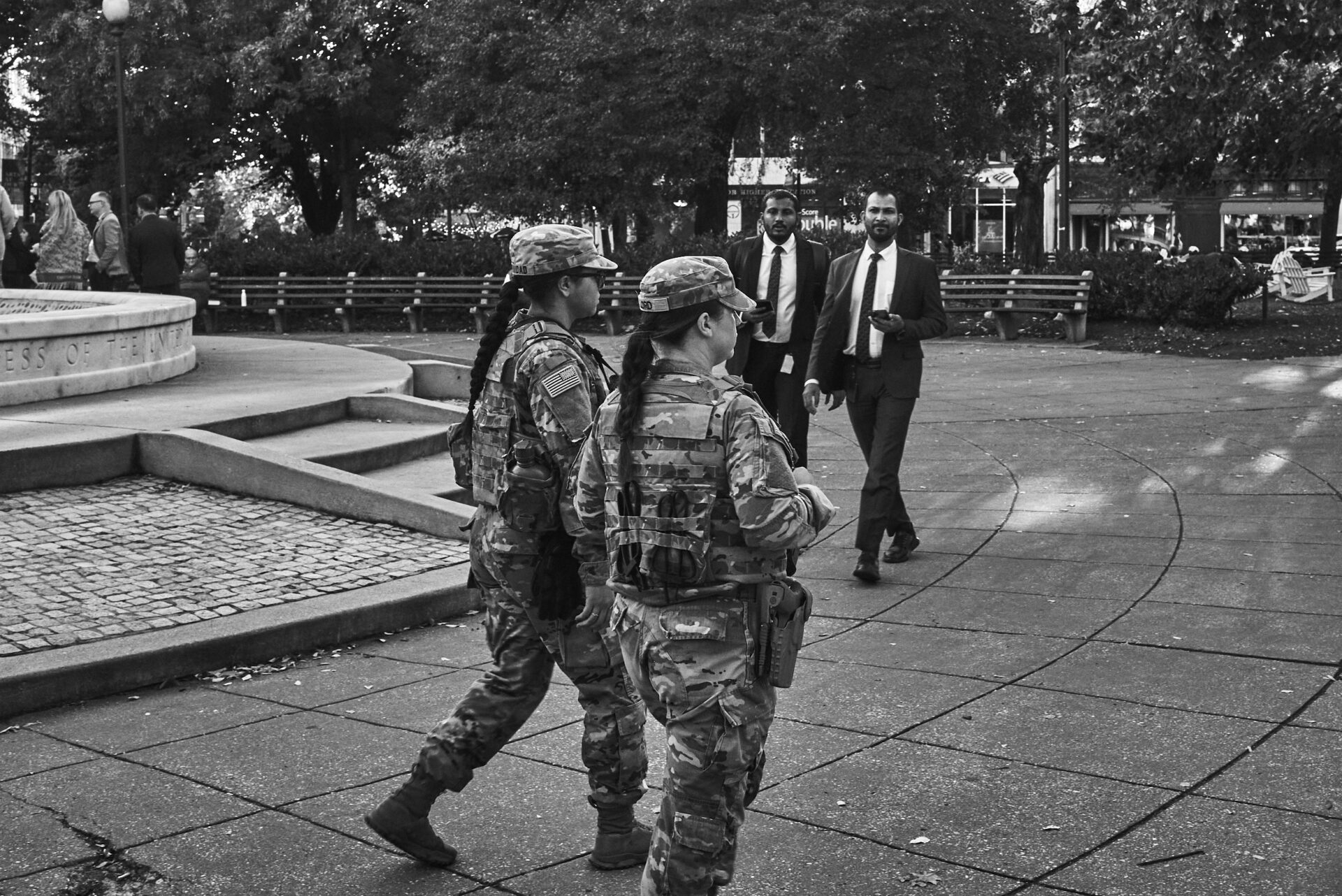 Two National Guardsmen pass by two men in identical suits